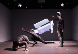 3 people in motion capture suites with projection behind
